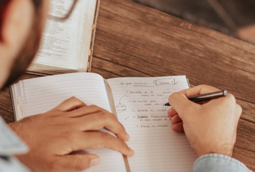 person in blue denim jeans writing on white paper